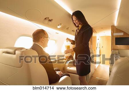 Stewardess serving passenger on private jet View Large Photo Image Picture - Stewardess serving passenger on private jet. Fotosearch