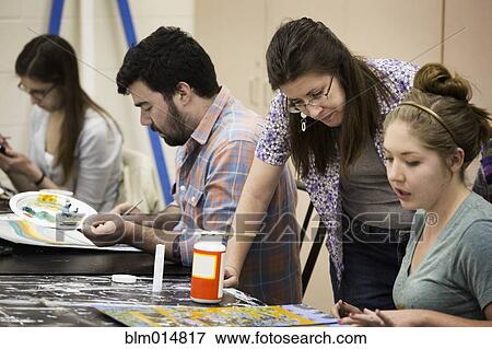 Stock Photo - Teacher helping student in art class. Fotosearch