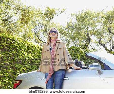 Stock Image - Woman leaning on convertible. Fotosearch