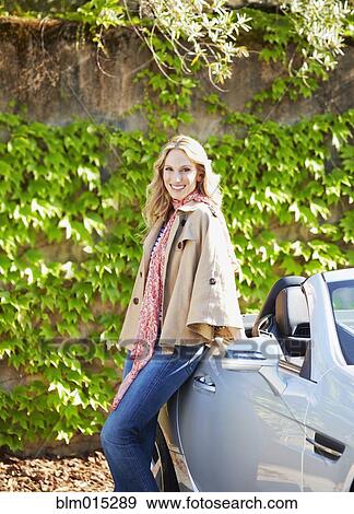 Stock Photo - Woman leaning on convertible. Fotosearch