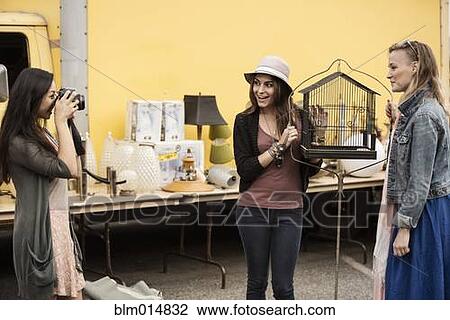 Woman photographing friends at flea market View Large Photo Image Stock Image - Woman photographing friends at flea market. Fotosearch