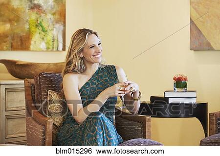 Stock Photograph - Woman sitting in chair drinking wine. Fotosearch