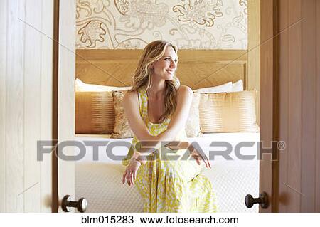 Stock Image - Woman sitting on bed. Fotosearch