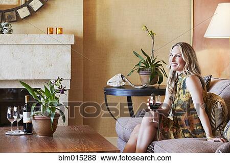 Woman sitting on sofa drinking wine View Large Photo Image Stock Photo - Woman sitting on sofa drinking wine. Fotosearch