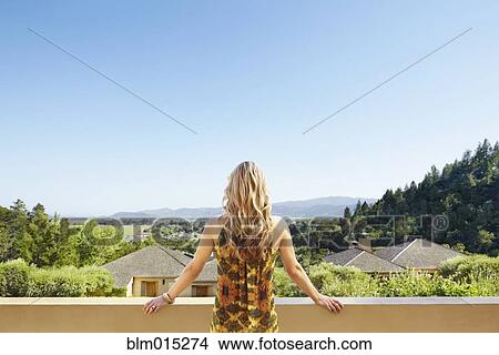 Picture - Woman standing on balcony. Fotosearch
