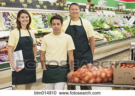 Stock Image - Workers in produce section of grocery store. Fotosearch