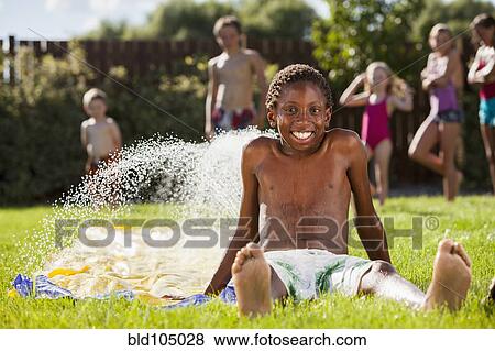Stock Photo - Black boy playing in water. Fotosearch