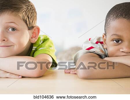 Stock Photograph - Bored boys leaning on table. Fotosearch