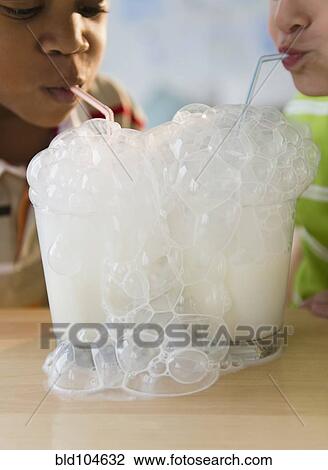 Stock Image - Boys blowing bubbles with milk together. Fotosearch