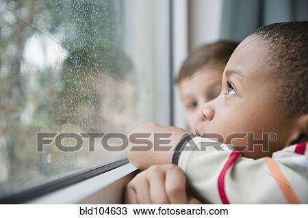 Stock Image - Boys looking out window together. Fotosearch