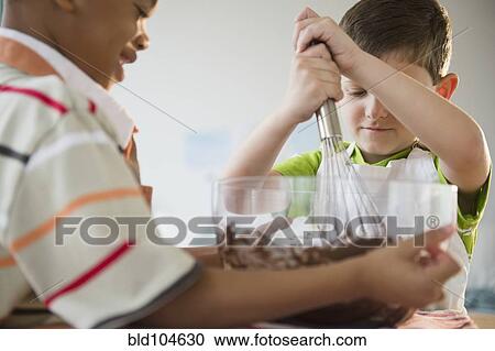 Stock Image - Boys mixing cake batter together. Fotosearch