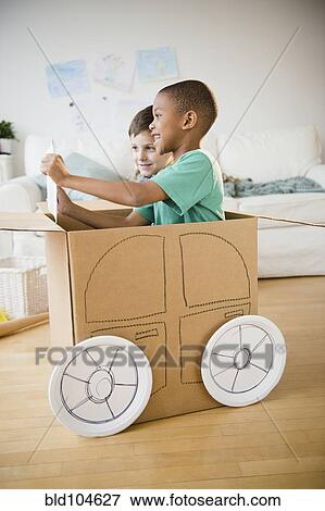 Boys playing in a cardboard car together View Large Photo Image Stock Photo - Boys playing in a cardboard car together. Fotosearch