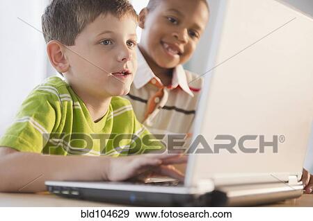 Stock Photo - Boys using laptop together. Fotosearch