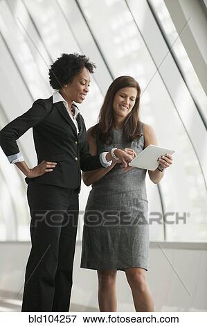 Stock Photo - Businesswomen using digital tablet together. Fotosearch