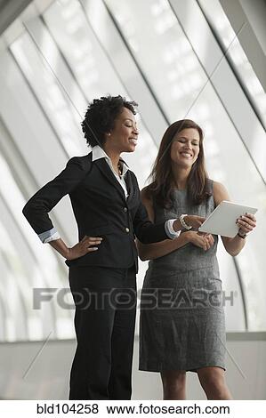 Stock Photo - Businesswomen using digital tablet together. Fotosearch