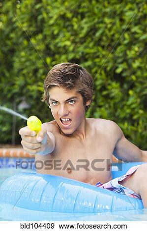 Stock Photo - Caucasian boy in swimming pool squirting water gun. Fotosearch