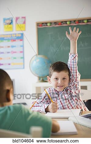 Picture - Caucasian boy raising hand in classroom. Fotosearch