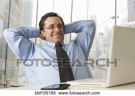 Caucasian businessman stretching at desk View Large Photo Image Stock Photography - Caucasian businessman stretching at desk. Fotosearch