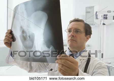 Stock Image - Caucasian doctor looking at hip x-ray. Fotosearch