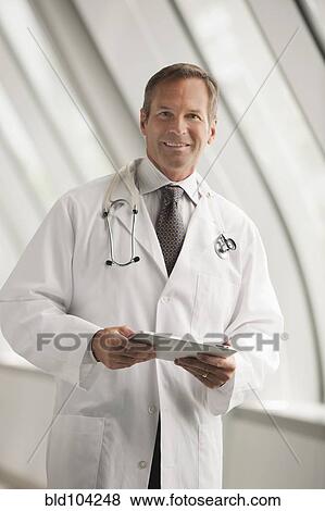 Stock Photo - Caucasian doctor using digital tablet in hospital corridor. Fotosearch