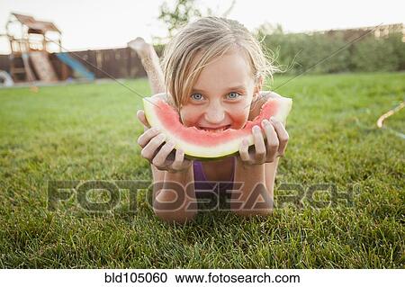 Stock Image - Caucasian girl eating watermelon. Fotosearch