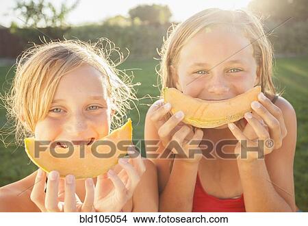 Picture - Caucasian girls eating cantaloupe. Fotosearch