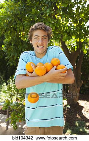 Stock Image - Caucasian holding and dropping oranges. Fotosearch