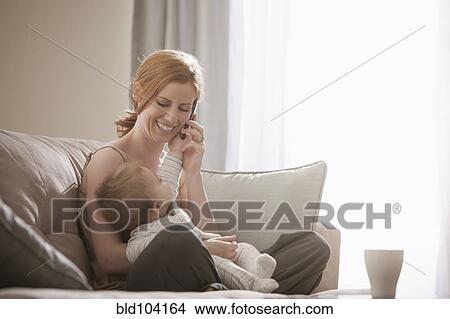 Picture - Caucasian mother holding son and talking on cell phone. Fotosearch