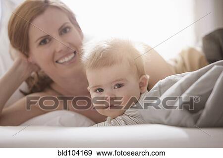 Stock Photo - Caucasian mother laying with son. Fotosearch