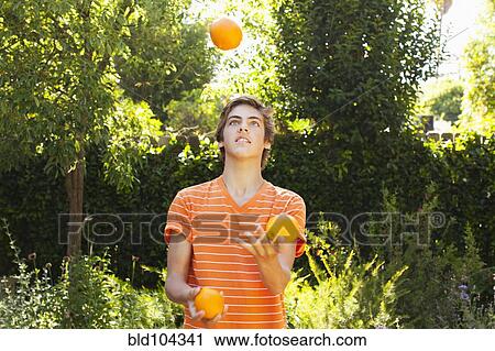 Stock Image - Caucasian teenager juggling oranges. Fotosearch