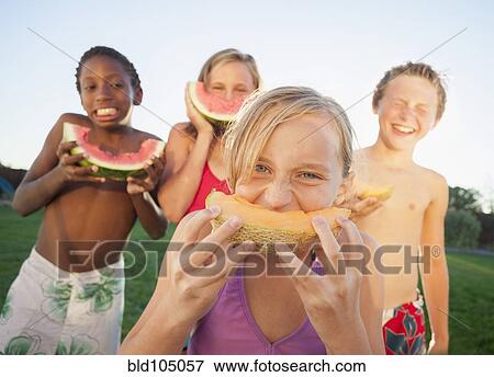Stock Photo - Children eating cantaloupe and watermelon. Fotosearch