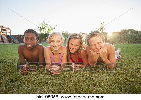 Stock Photo - Children laying in the grass together. Fotosearch