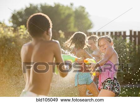 Stock Photo - Children squirting each other with water guns. Fotosearch