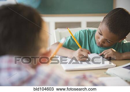 Stock Image - Children writing in classroom. Fotosearch