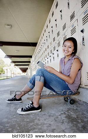 Stock Image - Chinese teenager on skateboard using digital tablet. Fotosearch