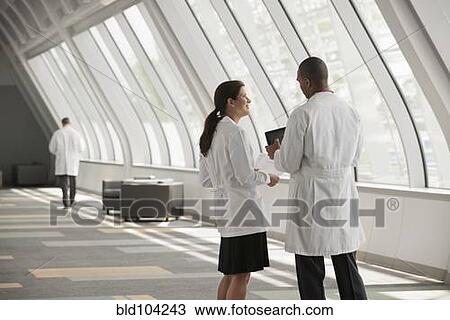 Stock Image - Doctors talking together in hospital corridor. Fotosearch