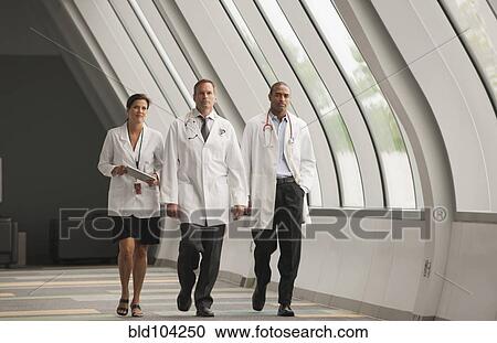 Stock Image - Doctors walking together in hospital corridor. Fotosearch