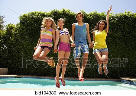 Stock Image - Friends jumping together near swimming pool. Fotosearch