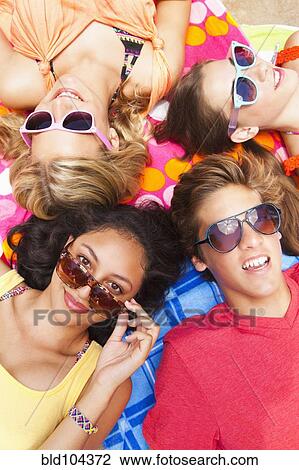 Stock Image - Friends laying outdoors together. Fotosearch