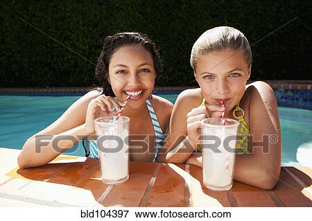 Stock Photo - Girls drinking lemonade near swimming pool. Fotosearch