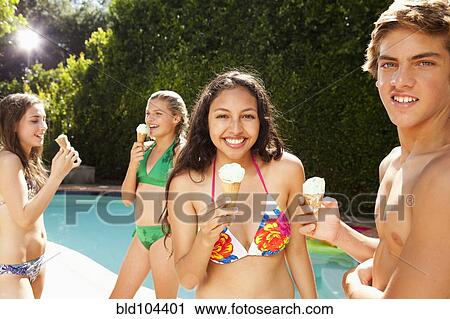 Stock Image - Girls eating ice cream cones near swimming pool. Fotosearch