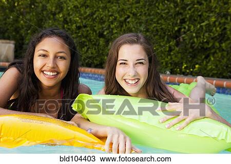 Stock Image - Girls in inflatable raft in swimming pool. Fotosearch