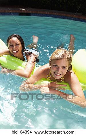 Picture - Girls laying on inflatable raft in swimming pool. Fotosearch