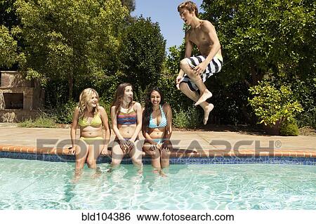 Stock Photograph - Girls watching teenage boy jumping in to swimming pool. Fotosearch