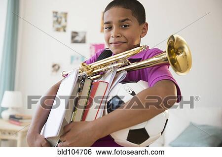 Hispanic boy carrying trumpet, books and soccer ball View Large Photo Image Stock Photograph - Hispanic boy carrying trumpet, books and soccer ball. Fotosearch