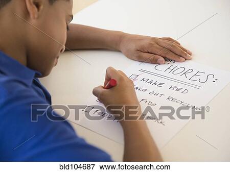 Stock Photo - Hispanic boy checking off chore list. Fotosearch