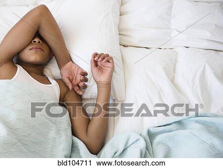 Stock Image - Hispanic boy laying in bed. Fotosearch