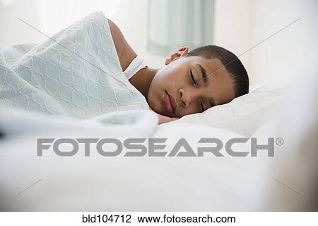 Stock Image - Hispanic boy laying in bed. Fotosearch