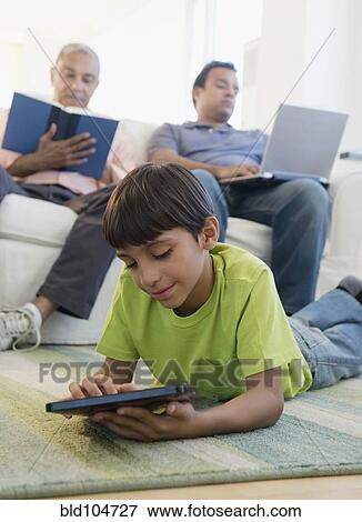 Stock Photo - Hispanic boy laying on floor using digital tablet. Fotosearch