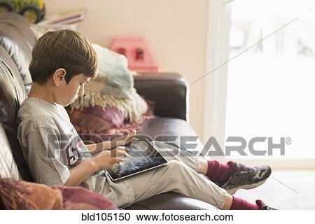 Hispanic boy on sofa using digital tablet View Large Photo Image Stock Image - Hispanic boy on sofa using digital tablet. Fotosearch